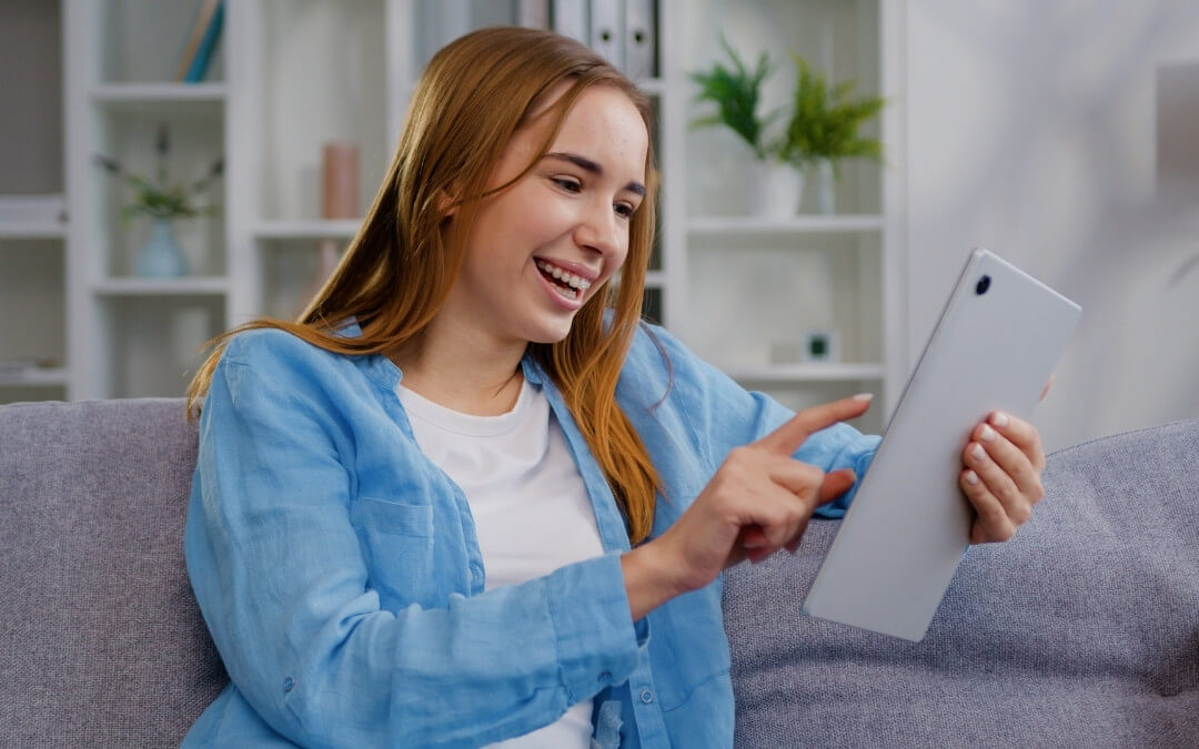 Teenagepige ser på sin iPad, mens hun sidder i sofaen.
