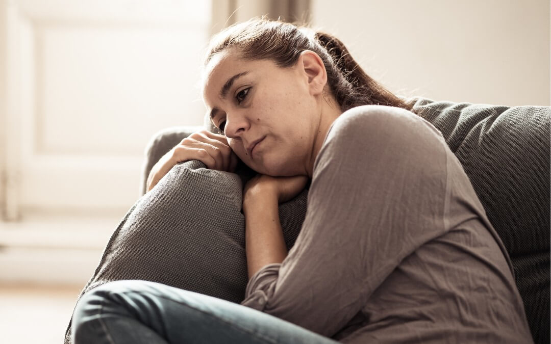 En kvinde sidder i en sofa og er i sorg efter hendes forældre er gået bort.